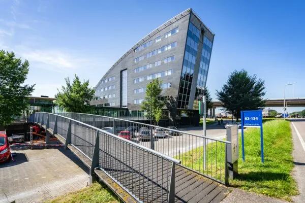 Modern kantoorgebouw aan de Rivium Promenade met opvallende architectuur en voetgangersbrug op de voorgrond.